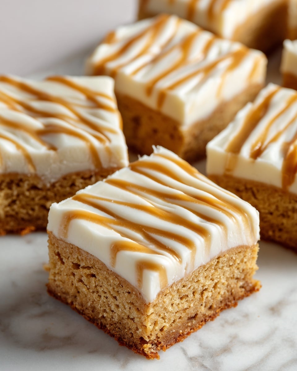 The image shows several square pieces of blondies stacked on a white marbled surface. Each blondie has two layers: the bottom layer is a soft, light brown cake with a slightly crumbly texture, while the top layer is a smooth, creamy white icing. On top of the icing are thin, wavy caramel-colored lines drizzled evenly across each piece. The blondies have clean-cut edges, and the focus is on one piece held slightly above the others, showing the thickness and texture clearly. photo taken with an iphone --ar 4:5 --v 7