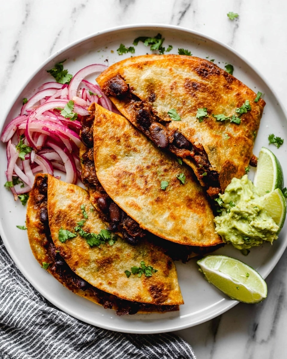 A white plate holds three golden-brown, crispy quesadillas folded in half, each filled with a dark, slightly charred mix of beans and meat visible along the edges. On the left side of the plate, there is a small pile of thinly sliced deep pink-red onions with a shiny texture, while on the right side, a small scoop of light green, creamy guacamole is placed next to two pale green lime wedges. Small green cilantro leaves are scattered over the quesadillas and plate, adding a fresh touch. The plate sits on a white marbled surface with a striped cloth partially visible at the bottom. Photo taken with an iphone --ar 4:5 --v 7