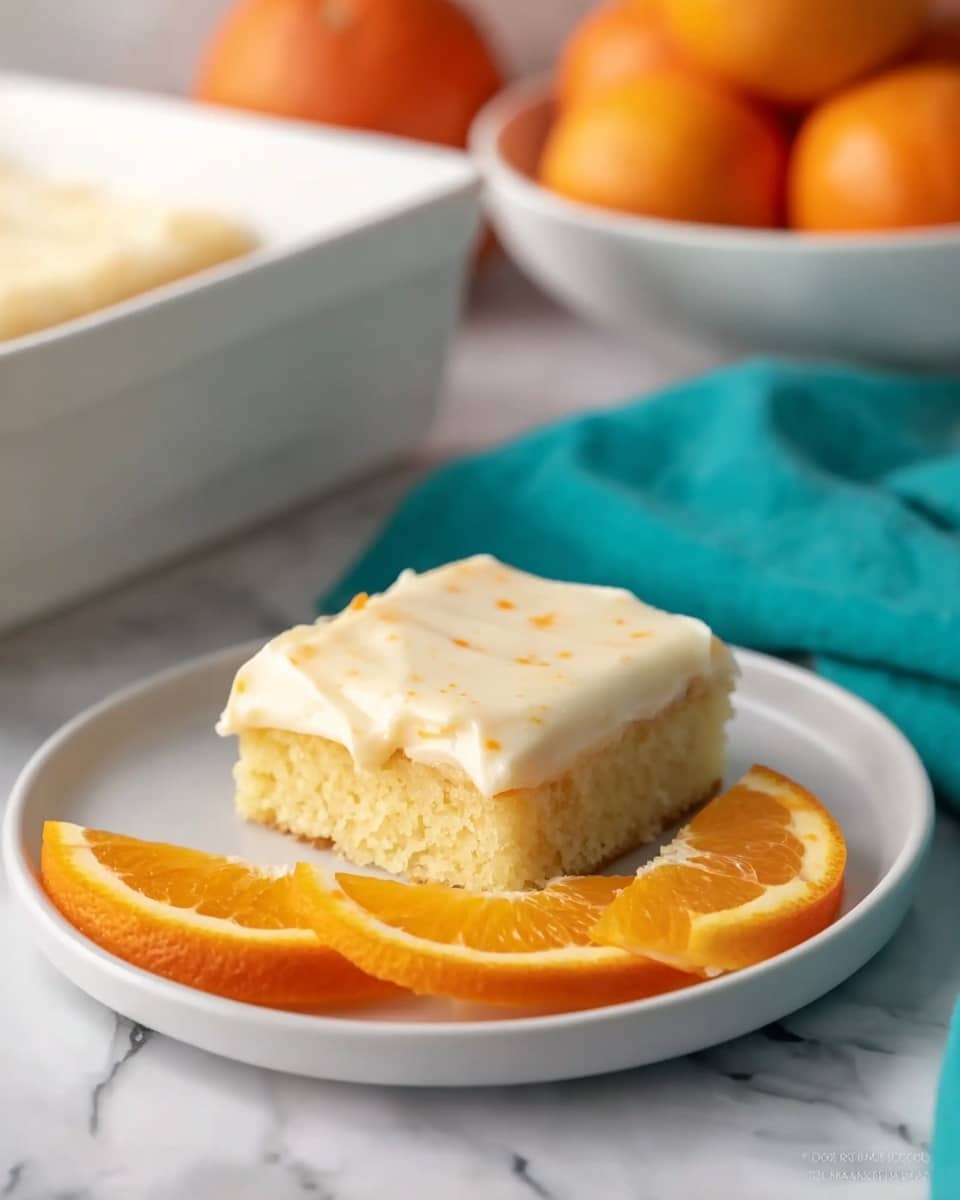 A single square piece of cake sits on a white plate, showing two layers: a bottom layer of moist, light yellow cake and a thick, creamy off-white frosting layer on top with a smooth texture and small orange specks throughout. Behind the cake, three bright orange slices are arranged in a row on the plate, adding a fresh, vibrant contrast. The plate rests on a white marbled surface. In the background, a teal cloth and a white dish filled with whole oranges are softly blurred, giving a cozy kitchen feel. Photo taken with an iphone --ar 4:5 --v 7