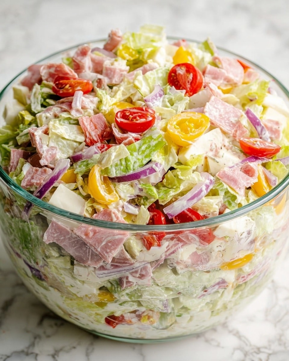 A clear glass bowl filled with a colorful layered salad rests on a white marbled texture. The salad has roughly three layers: the base is a mix of light green and pale white lettuce pieces, the middle layer has sliced purple onions, halved red cherry tomatoes, and yellow pepper strips, and the top layer shows scattered chunks of pale cheese and small pieces of pink deli meat. The salad is coated lightly with a creamy dressing, making the ingredients appear fresh and moist. Photo taken with an iphone --ar 4:5 --v 7