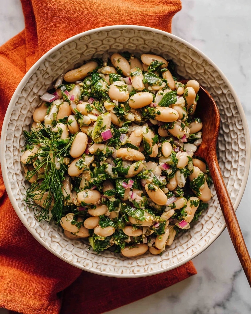 A white bowl with a honeycomb pattern on the inside holds a bean salad made of several beige beans mixed with finely chopped green herbs and small bits of pink onion, creating a fresh texture. The salad looks lightly coated with oil or dressing, giving it a slight shine. A wooden spoon rests inside the bowl on the right side, partially buried in the salad. The bowl sits on a white marbled surface with an orange cloth draped partially beneath it. photo taken with an iphone --ar 4:5 --v 7