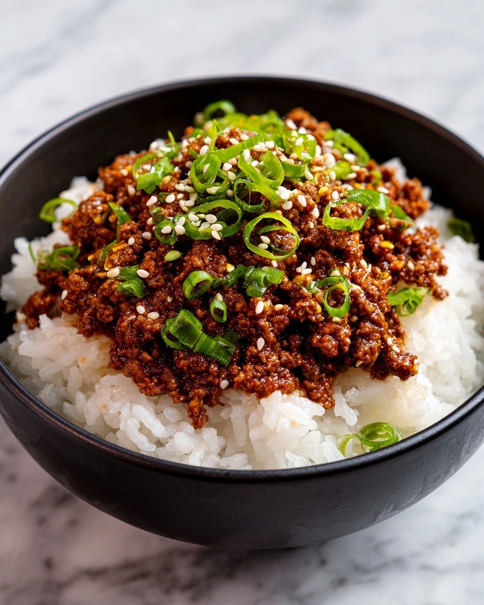 A close-up of a black bowl filled with two layers: the bottom layer is white fluffy rice with a slightly sticky texture, and on top is a thick layer of dark brown cooked ground meat mixed with sauce, giving it a shiny look. Sprinkled over the meat are small green chopped scallions and white sesame seeds, adding texture and color contrast. The bowl sits on a white marbled surface. photo taken with an iphone --ar 4:5 --v 7