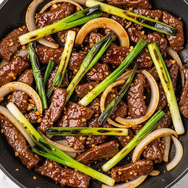 The image shows a close-up of a cooking pan filled with stir-fried beef pieces coated in a shiny, dark brown sauce. Mixed in are long, soft white onion slices and bright green cooked scallion pieces layered evenly throughout the pan. The beef has a glossy texture with slightly charred edges, while the onions look tender and the scallions add a fresh color contrast. Small bits of minced garlic and sauce droplets are visible, enhancing the rich, glossy look of the dish. The background is a white marbled texture. photo taken with an iphone --ar 4:5 --v 7