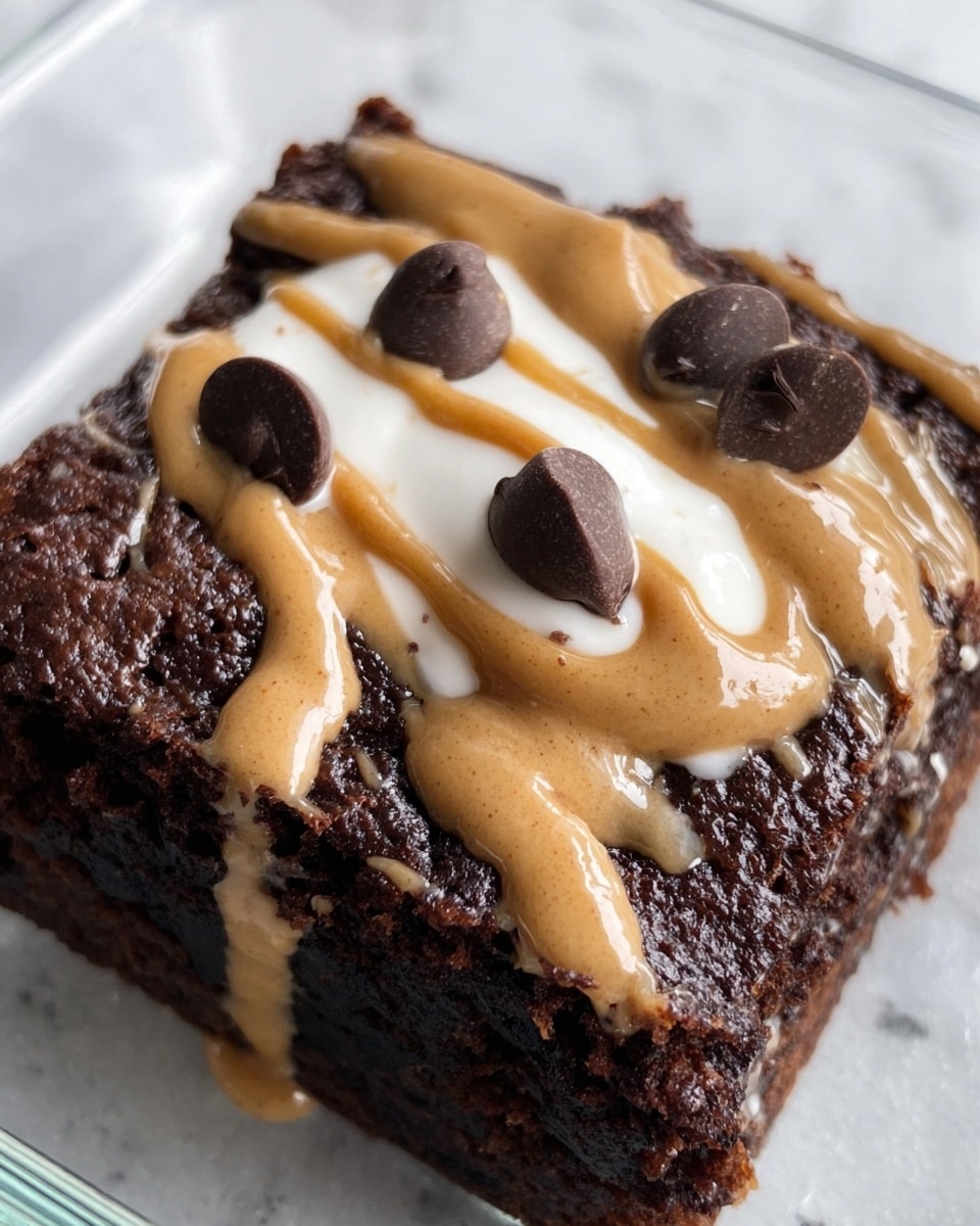 A square piece of dark brown brownie sits at the bottom layer with a moist, dense texture visible. On top, there is a shiny, tan-colored peanut butter drizzle spread unevenly across, creating streaks. Above the peanut butter, there is a dollop of white cream or yogurt with a smooth and soft texture placed near the center. Scattered on top are several large, glossy dark chocolate chips, some partially sunk into the creamy layer. The brownie is inside a clear glass dish, and the scene is set on a white marbled texture. photo taken with an iphone --ar 4:5 --v 7