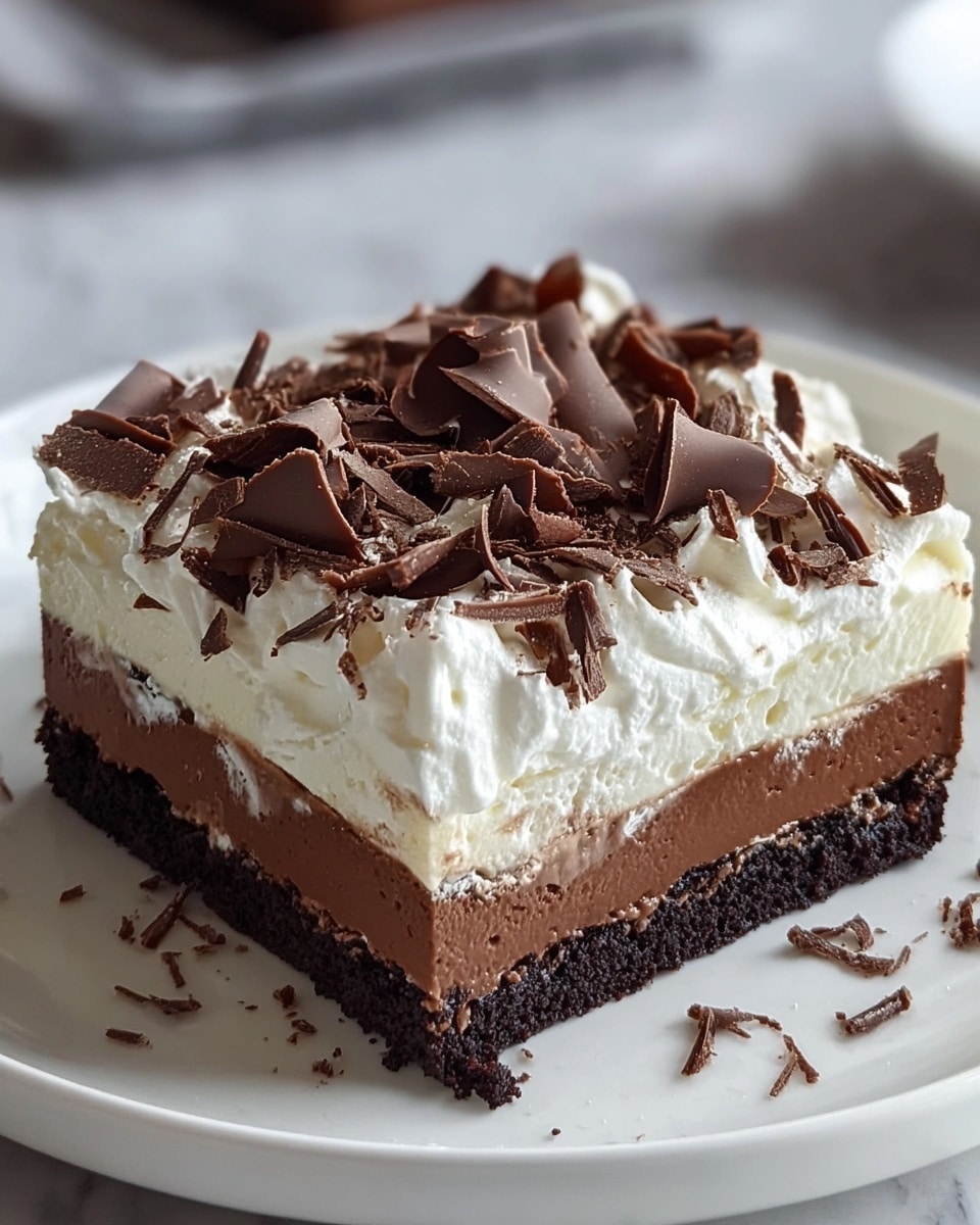 A square dessert bar is shown with four clear layers on a white plate set on a white marbled surface. The bottom layer is a dark, crumbly chocolate crust. Above that is a thick, smooth milk chocolate layer. The next layer is a thick white cream with soft peaks that look fluffy. On top, large curls and smaller shavings of dark chocolate are scattered across the creamy surface, adding texture and richness. The sides reveal the clean, even layers making the dessert look very rich and inviting. Photo taken with an iphone --ar 4:5 --v 7